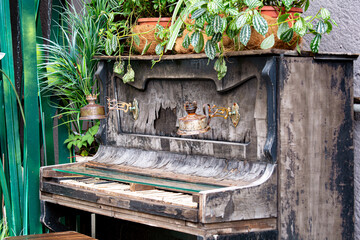 old piano with kerosene lamps and vases with plants, decor for a street cafe.