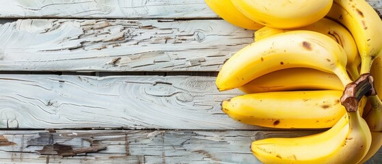   A ripe batch of bananas sits on a wooden table near an unripe set