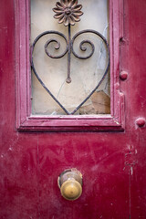 Metal heart shape decoration on an old modernist crimson door locked detail