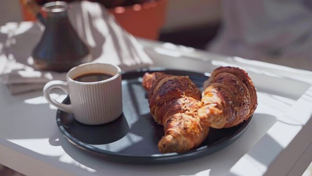 Close up of a coffee and croissants breakfast set on a white tray on a sunny day