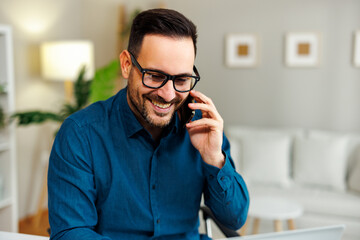 Young happy man talking on the phone at home - 775374090