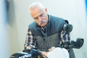 Fototapeta premium a senior man repairing motorbike outdoor