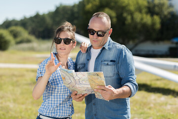 happy couple looking at map - obrazy, fototapety, plakaty