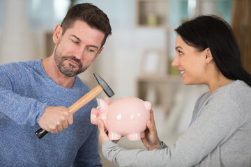 couple holding hammer and piggy bank