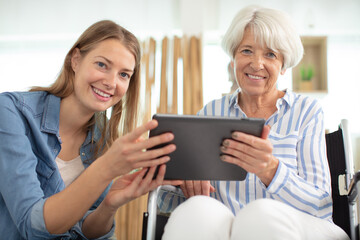 aged woman and her adult daughter using tablet