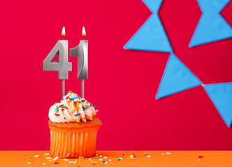 Birthday cupcake with candle number 41 on a red background with blue pennants
