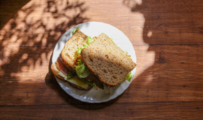 木材背景の皿にのせたオーガニックパンのサンドイッチ - obrazy, fototapety, plakaty