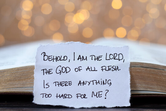 Handwritten Christian quote for God's supreme power, authority, and greatness over creation in front of open holy bible with bokeh background. Close-up. Jesus Christ's glory, love, and care concept.