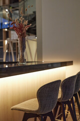 Vertical background image of bar counter in modern cafe interior with tall chairs and led lighting...