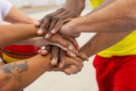 Basketball anonymous teammates place their hands together in a symbol of unity and shared commitment before starting their street basketball session - Powered by Adobe
