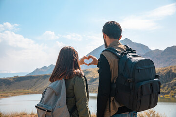 A loving traveling couple with backpacks makes a heart with their hands. stock photo