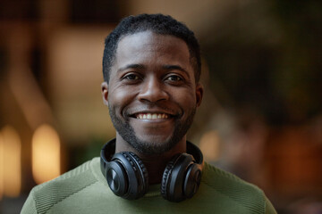 Front view portrait of African American young man with headphones smiling at camera blurred...