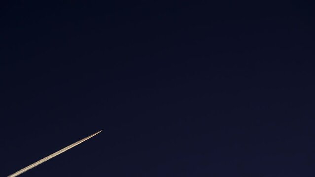 Airplane at cruising altitude with contrail against sky. Chemtrail or condensation trails.