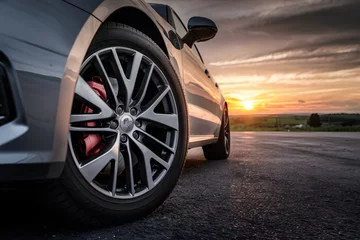 Fotobehang Tire close up with sunset backdrop creates dramatic automotive image © NBXt
