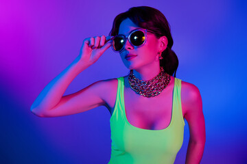 Photo of girl in retro style look aside touch sunglass isolated violet neon color background