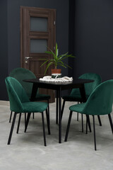 Black wooden table combined with green wooden chairs with soft fabric upholstery. There is a green...