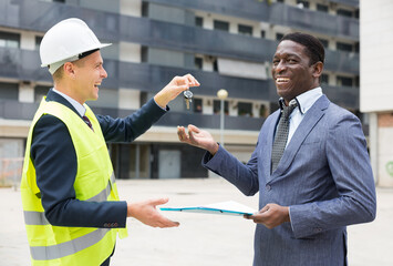 Happy builder gives the keys to the new home african american businessman