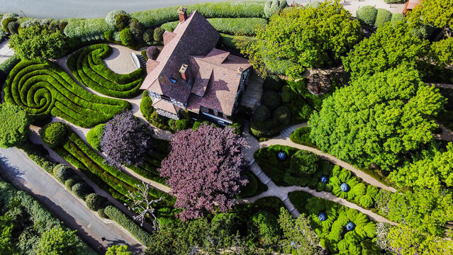 Drone view on Part of Etretat gardens with amazing curves of topiary bushes and red leaves trees and house