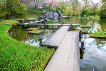 Zigzag bridge in Japanese garden in Hasselt,  cascade of waterfalls in distance