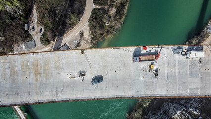 Construction of a high bridge over the river, aerial drone view. Workers and machines on...