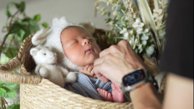 The scene where an 8-day-old Taiwanese baby wrapped in a blue wrap and wearing a rabbit ear hat is laughing and taking a newborn photography 青いおくるみに巻かれた台湾人の生後８日の赤ちゃんがニューボーンフォトを撮影されている光景