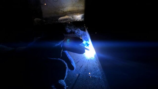 The process of electric welding of metal structures. Bright flames, smoke and sparks. Master in work gloves.