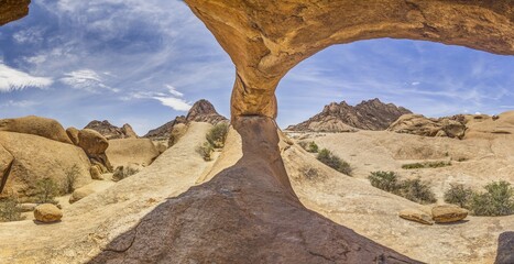 Panoramic picture of the famous stone arch at the Spitzkoppe in Namibia during the day with blue sky