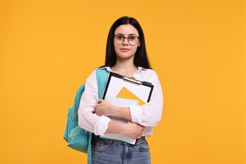 Student with notebooks and clipboard on yellow background - obrazy, fototapety, plakaty