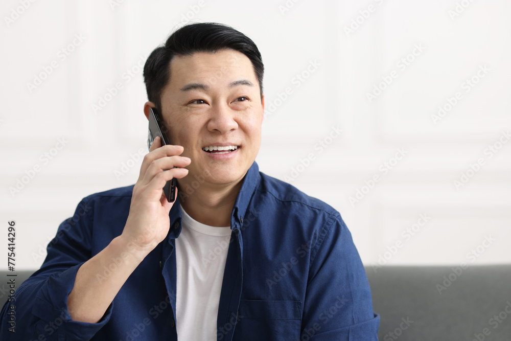 Sticker Portrait of smiling businessman talking by smartphone indoors. Space for text