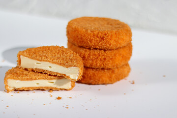 A stack of fried camembert with one cutter cheese on white table
