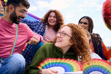 Group of diverse young people smiling in gay pride festival day holding rainbows fans. Friends of LGBT community cheerful and having fun outdoor. Lesbian, homosexual, transgender and non-binary