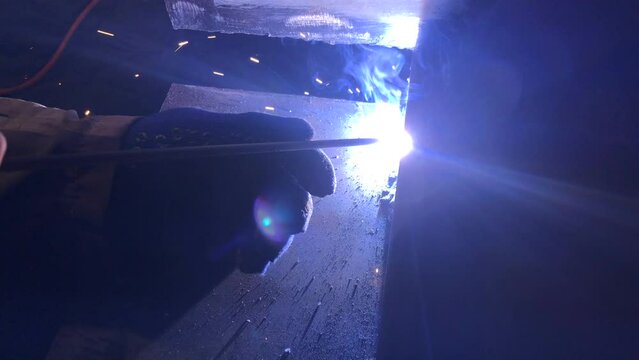 Process of electric welding of metal structures. Bright flames, smoke and sparks. Master in work gloves.