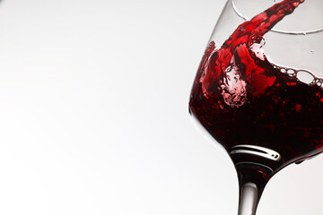 Pouring tasty red wine in glass on white background, closeup. Space for text