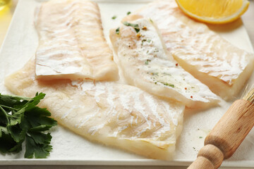 Fresh raw cod fillets with spices and brush on plate, closeup