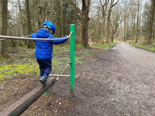 Fototapeta premium Little toddler climbing and playing in the forest, Flensburg northern city in Germany
