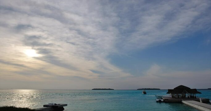Beautiful sunset timelapse with water villas in the Maldives in the background. The clouds are moving