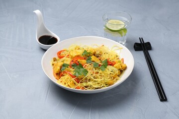 Stir-fry. Delicious cooked noodles with chicken and vegetables in bowl served on gray textured table