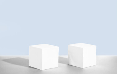 Fototapeta premium Cosmetic light blue background with geometric shapes. Two white cement cubic podiums. Mockup for the demonstration of cosmetic products