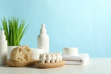Different bath accessories and houseplant on white table against light blue background. Space for text