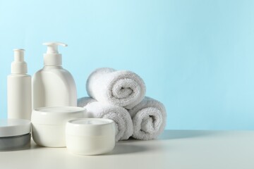 Different bath accessories on white table against light blue background. Space for text