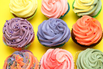 Delicious cupcake with bright cream on yellow background, flat lay