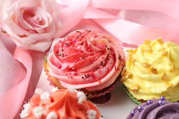 Delicious cupcake with bright cream on pink fabric, closeup