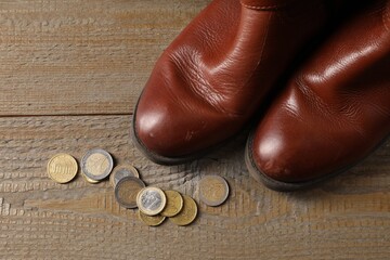 Poverty. Old boots and coins on wooden table, top view - obrazy, fototapety, plakaty