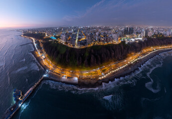 Panoramic aerial view captured with a drone, of the Miraflores district, in Lima, Peru.  The cliffs, the "Costa Verde" highway, the Miraflores boardwalk and the Pacific Ocean with the sky at sunset.