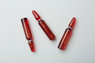 Glass ampoules with liquid on white background, top view