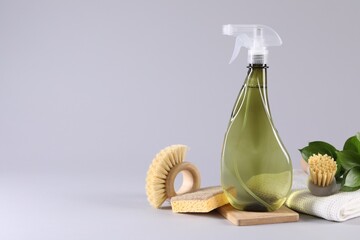 Bottle of cleaning product, rag, sponges and brushes on light grey background. Space for text - obrazy, fototapety, plakaty