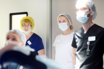 A surgeon, an assistant, an intern and a nurse observe the progress of a surgical operation on a...