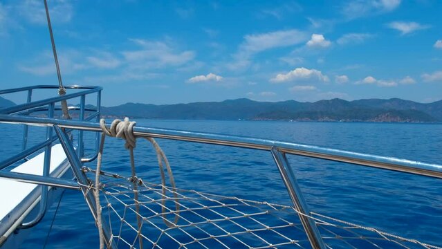 Board of fishing yacht on ocean surface. A nice motor boat floating in the blue sea against mountains in summer.