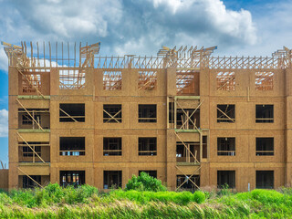 Exterior of a four-story apartment building under construction on a partly cloudy afternoon in...