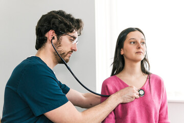 A focused doctor conducts a stethoscope exam on a female patient, a routine part of a thorough medical check-up